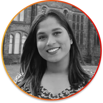Portrait of a smiling woman outdoors, with a brick historic building in the background.