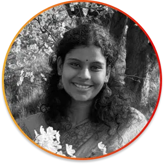 Circular avatar portrait of a smiling woman with dark curly hair outdoors among trees, wearing a floral top.